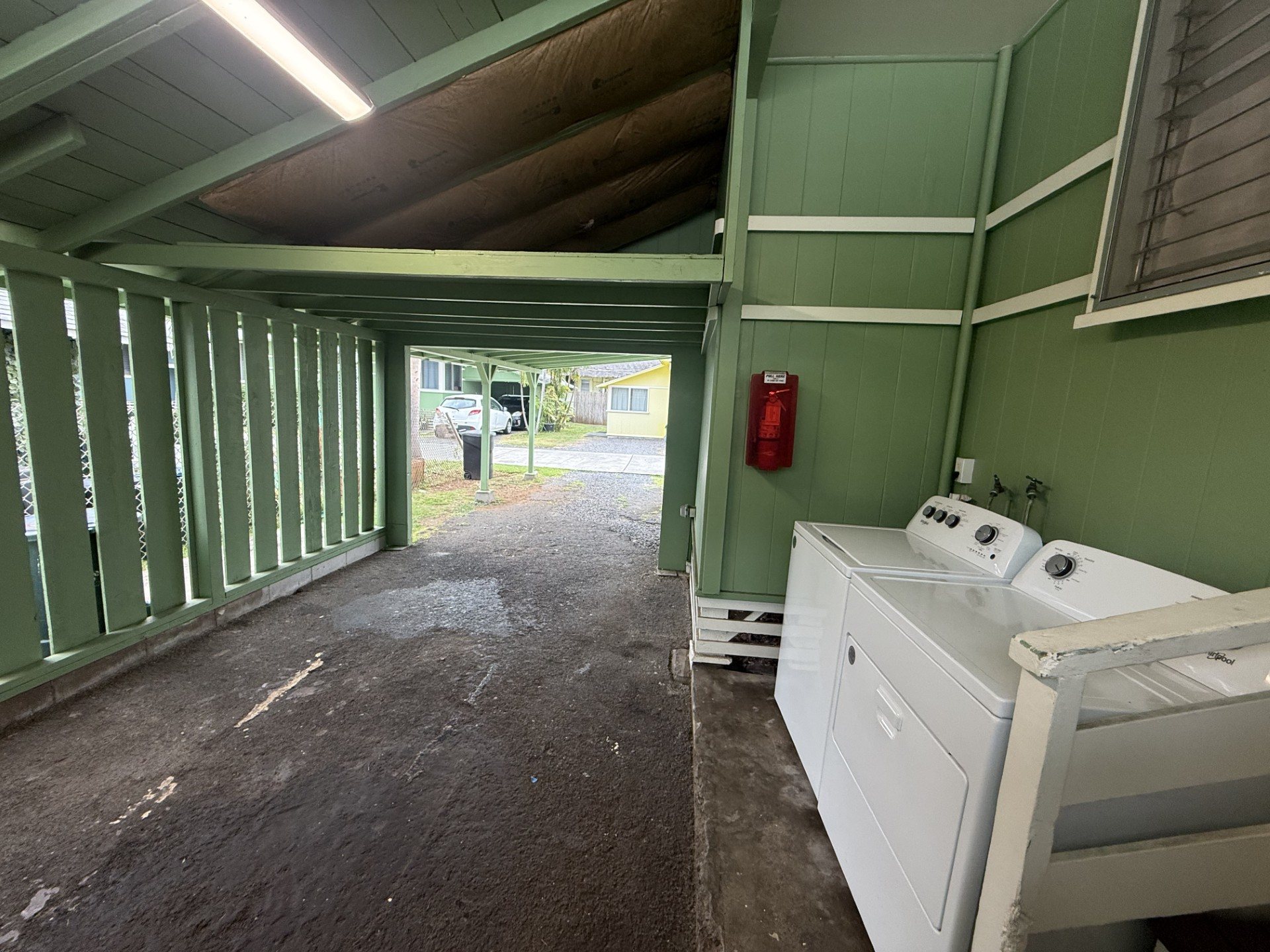 A room with a white appliance and a red fire extinguisher on the wall.